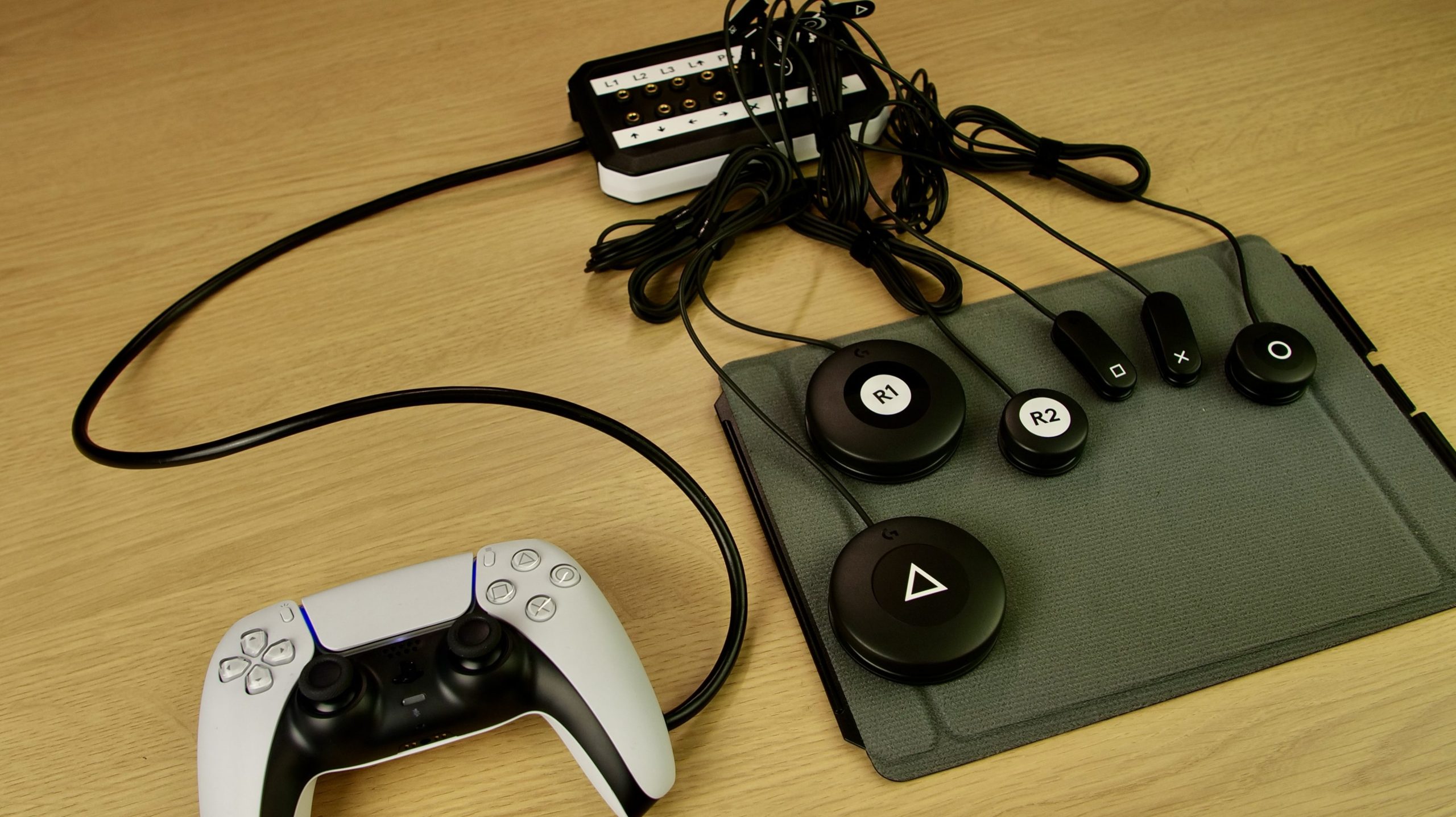 Photo showing the 19-switch DualSense interface with switches and a hook and loop board from the Logitech G Adaptive Kit being used alongside it.